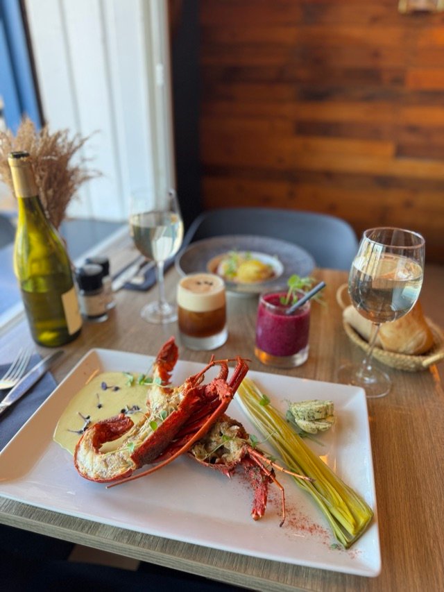 Table dressée avec langouste, verrines et cocktails, vue sur la baie