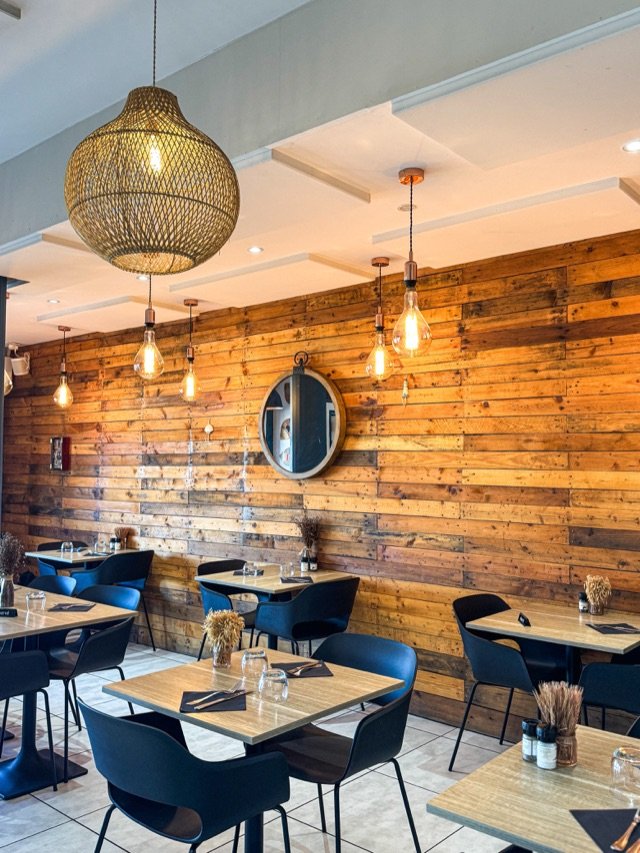 La salle du restaurant, mur en bois de palette et suspensions en rotin