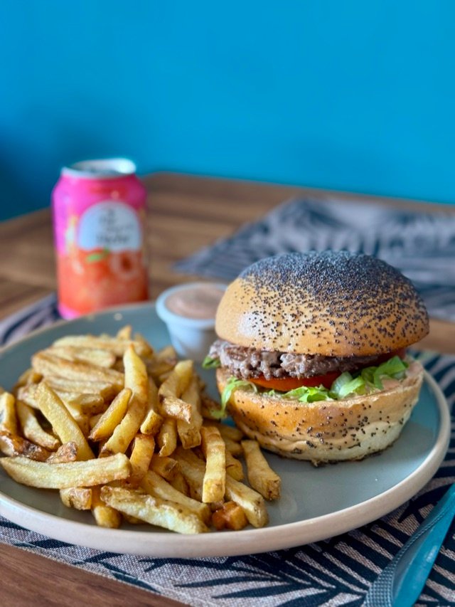 Burger aux graines de pavot et frites sur une table de la salle