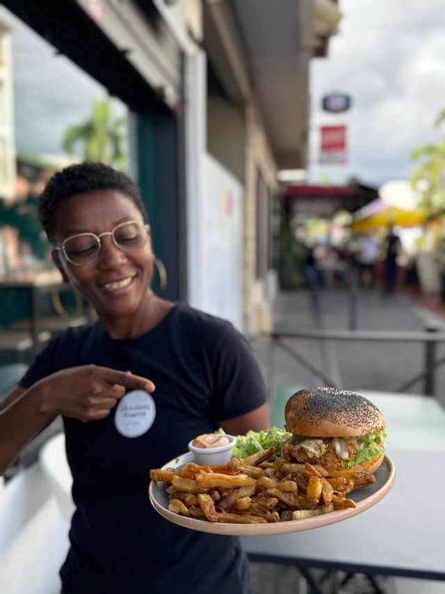 Membre de l'équipe présentant un burger-frites en terrasse