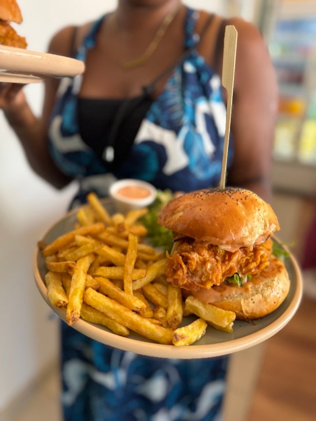 Cliente portant un plateau burger-frites dans la salle