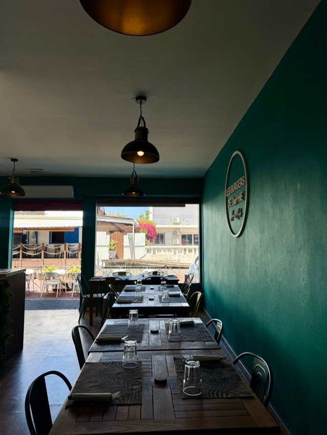 La salle du restaurant, tables alignées le long du mur vert