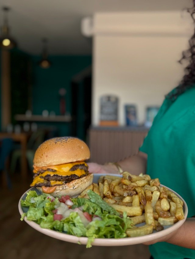 Burger au cheddar et frites maison, salle en arrière-plan