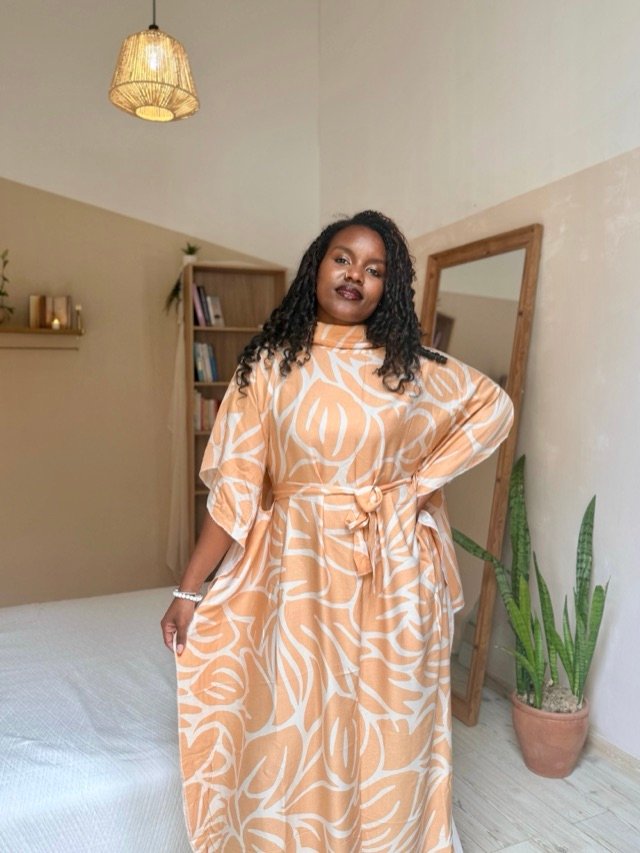 Robe abricot à motif graphique blanc, ceinturée à la taille, dans un intérieur clair