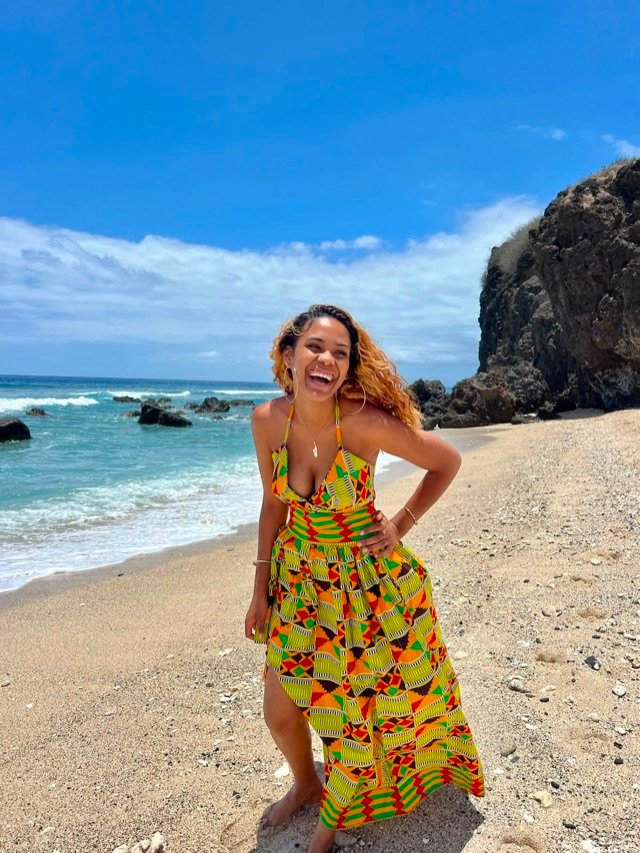 Robe longue en wax jaune et vert, sur le sable au pied de la falaise