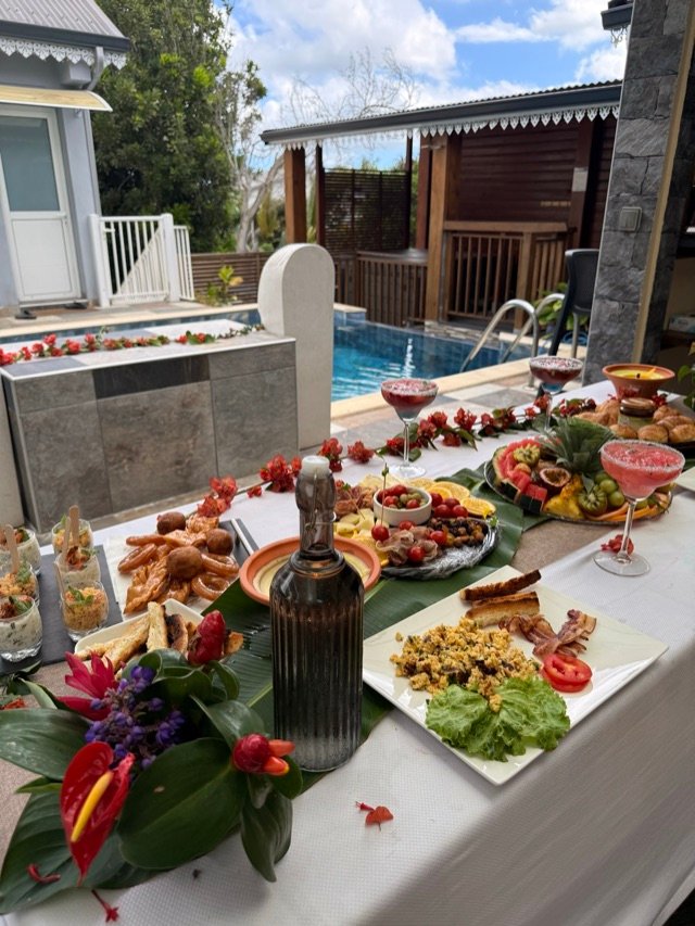 Table de brunch dressée le long de la piscine, décor de fleurs tropicales
