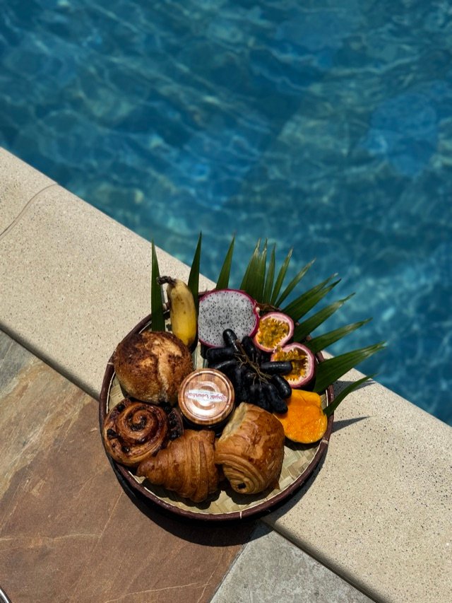 Plateau de viennoiseries et de fruits frais posé au bord du bassin