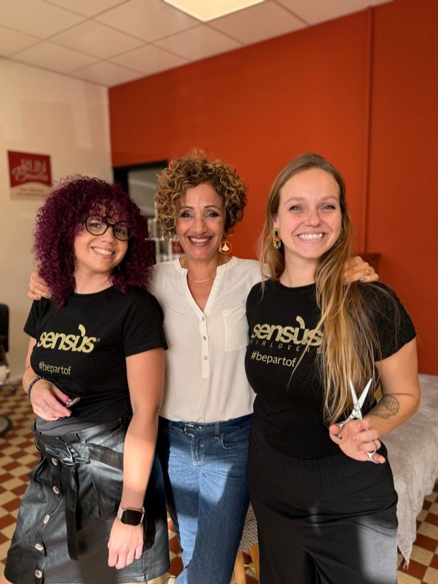 L'équipe du salon réunie devant le mur ocre, ciseaux à la main