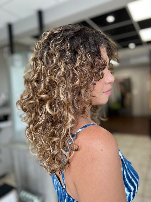Chevelure bouclée blonde de profil, après coupe et coiffage