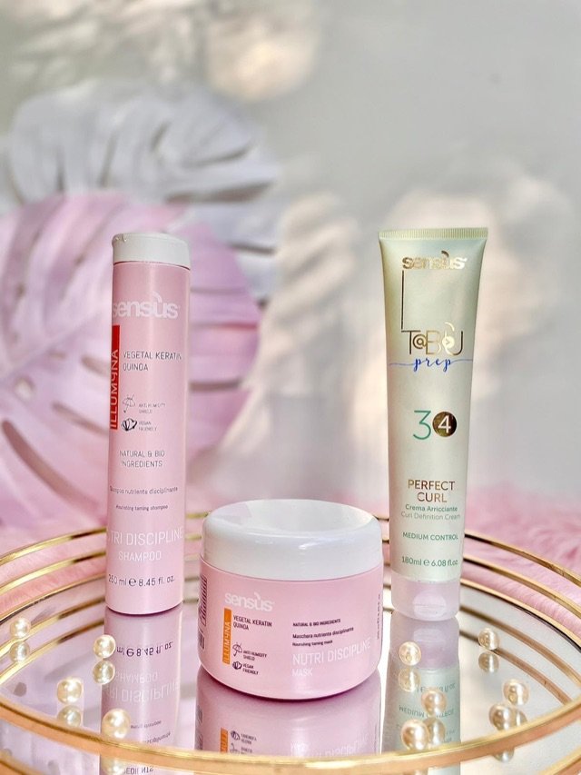 Shampooing, masque nourrissant et crème de définition des boucles, présentés sur un plateau